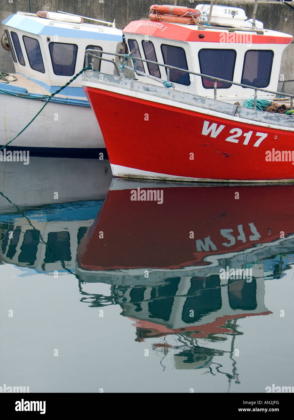 Two fishing boats moored in the harbour of Union Hall West Cork Ireland with reflections in the