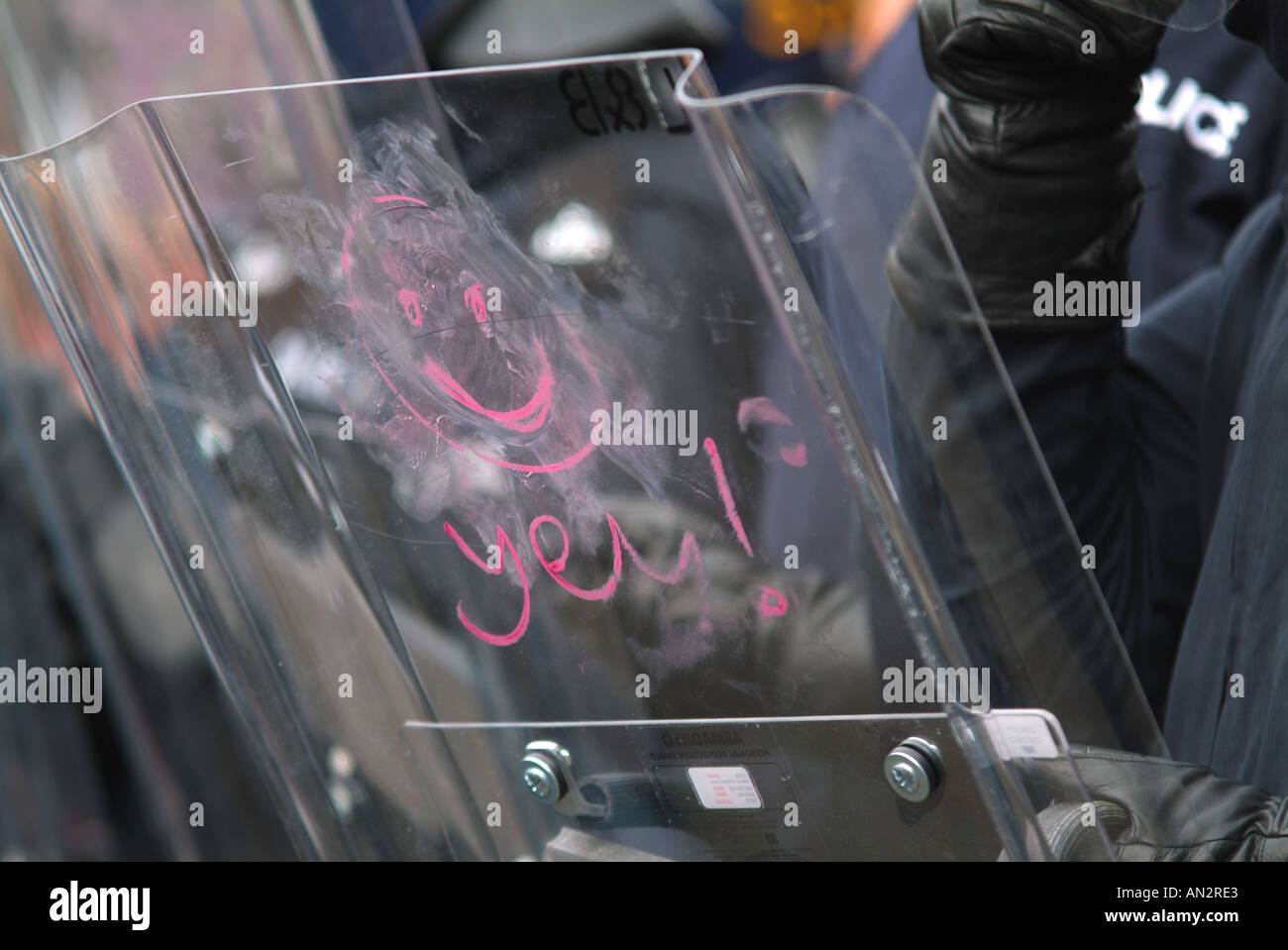 Smiley face drawn with lipstick on a riot policeman's shield Stock Photo