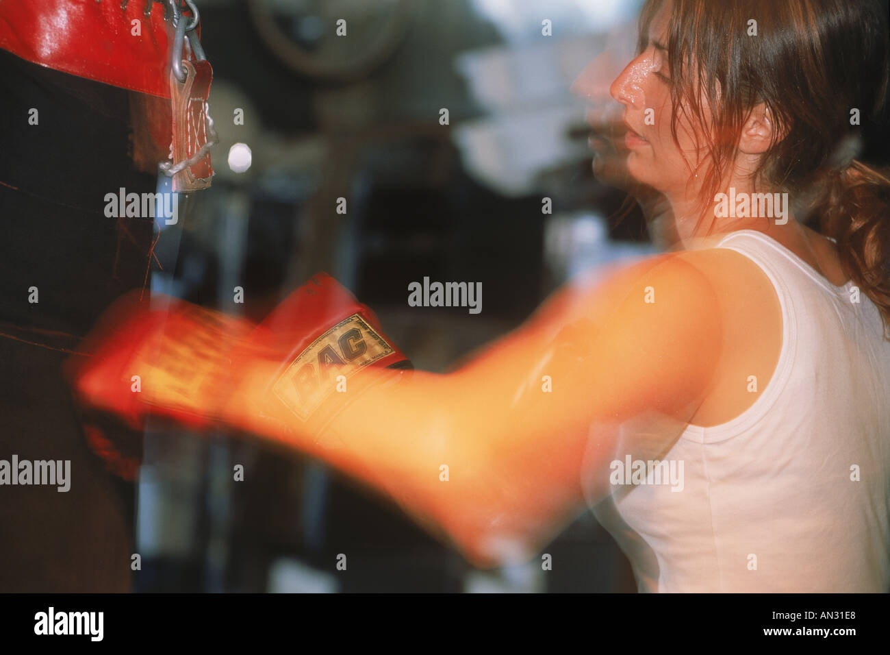 Woman hitting punching bag with boxing gloves Stock Photo Alamy