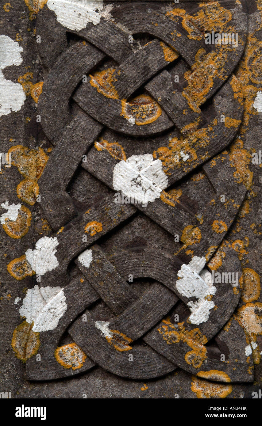 Celtic lace design covered by white and yellow lichen on a dark tombstone Stock Photo