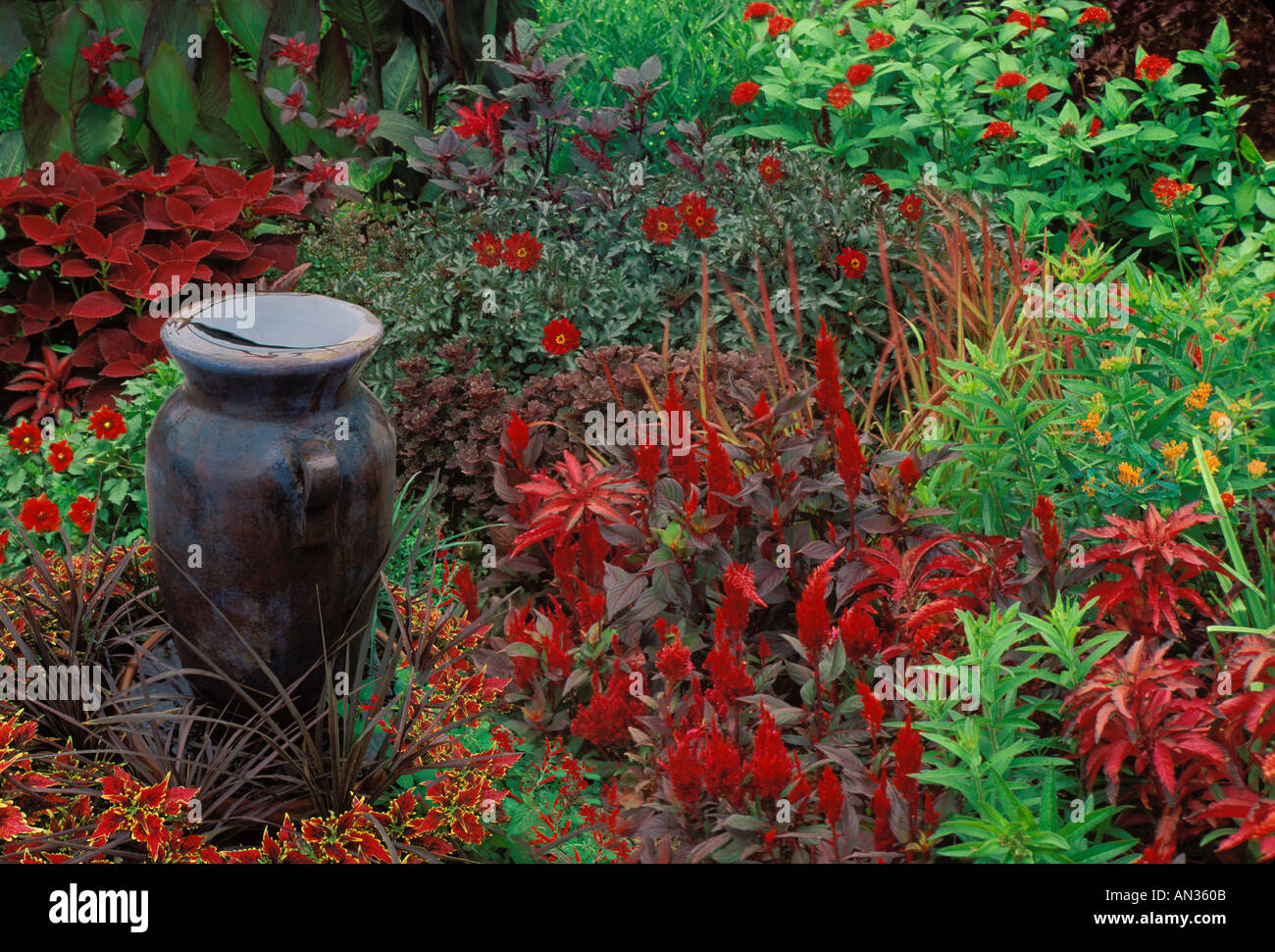 Flower garden in vibrant red and orange colors and tall ceramic vase as water fountain Missouri USA Stock Photo