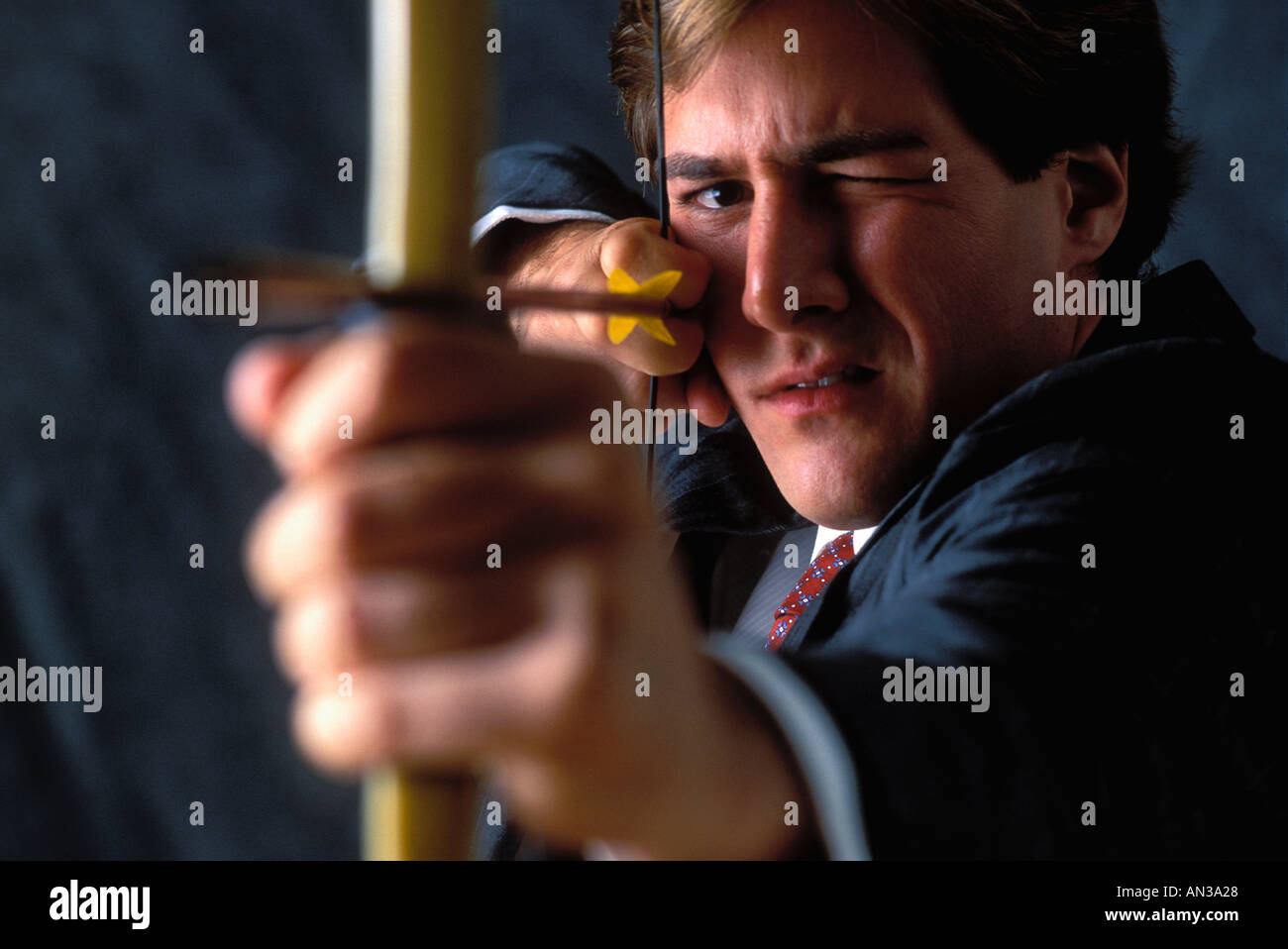 Blindfolded male executive aiming bow and arrow at target Stock Photo