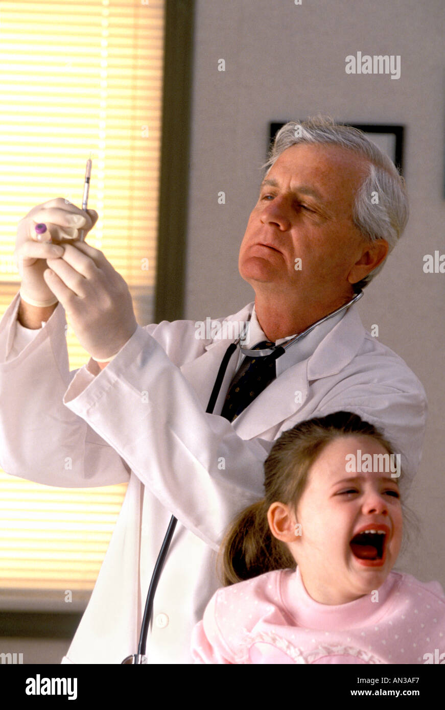 Doctor administering a vaccination to crying little girl Stock Photo