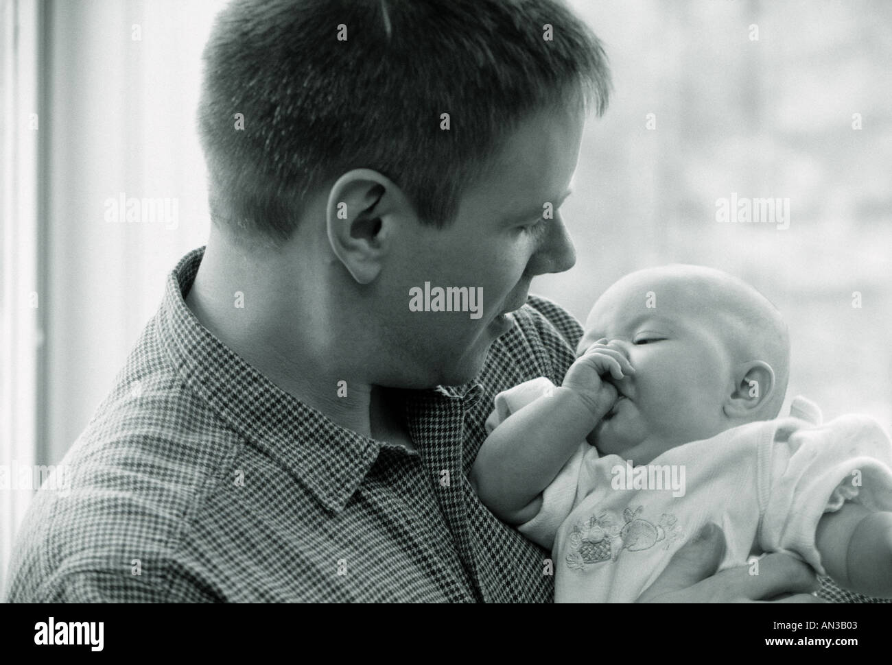 Black and white  portrait of aCaucasian father holding His newborn infant sucking thumb Stock Photo