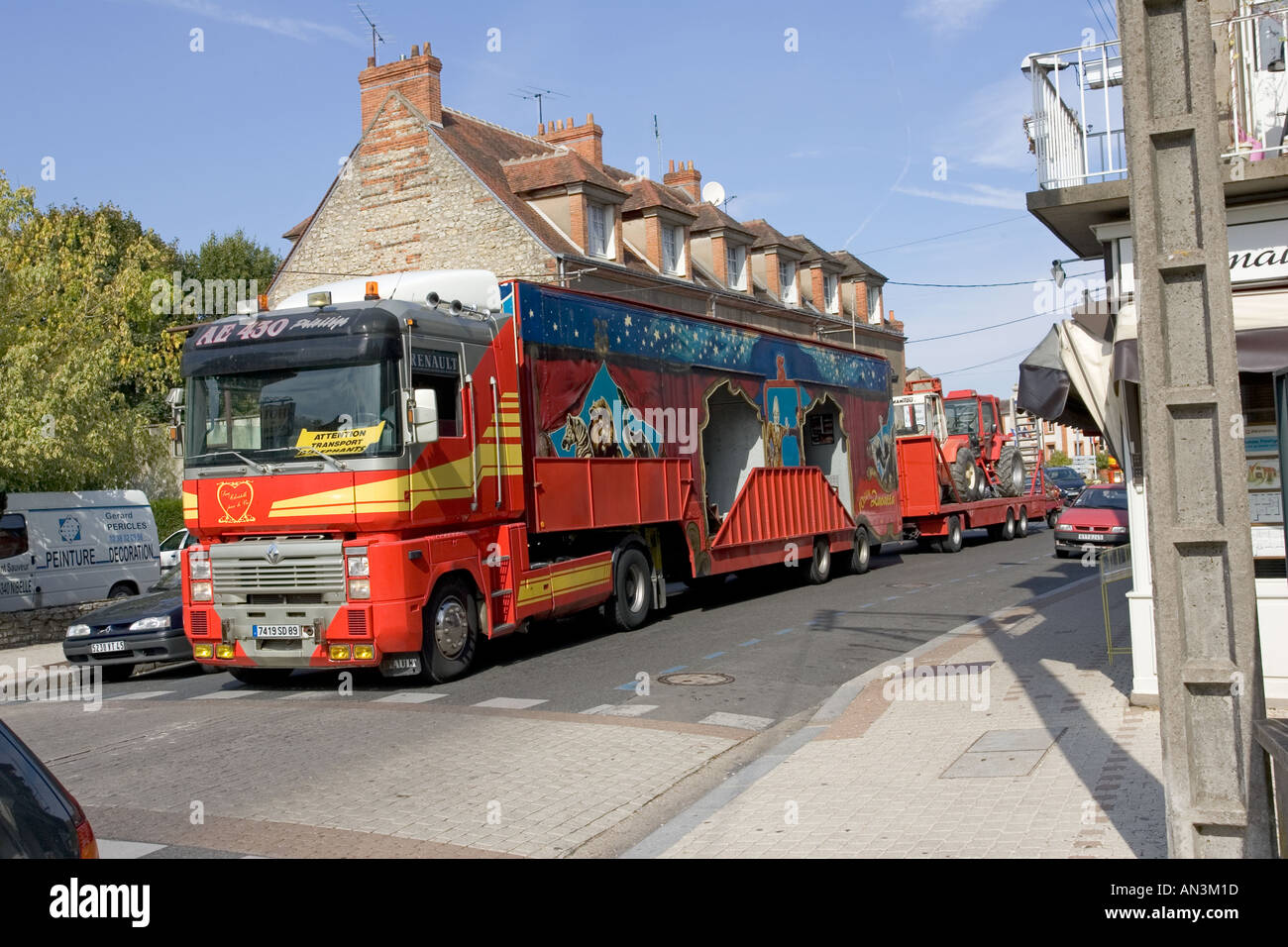 Huge red circus trucks and trailers blocking traffic in narrow streets of Chateauneuf sur Loire France Stock Photo