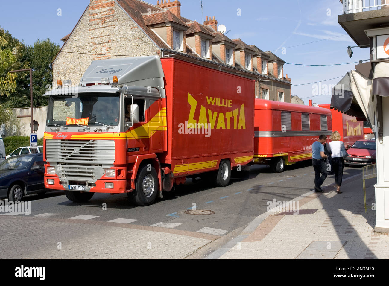 Huge Willie Zavatta red circus trucks and trailers blocking traffic in narrow streets of Chateauneuf sur Loire France Stock Photo