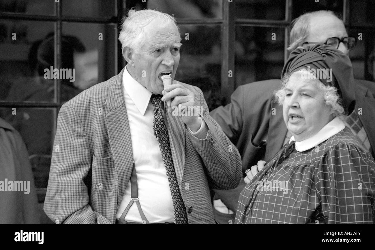 Old man eating icecream cornet in the street with lady. Stock Photo