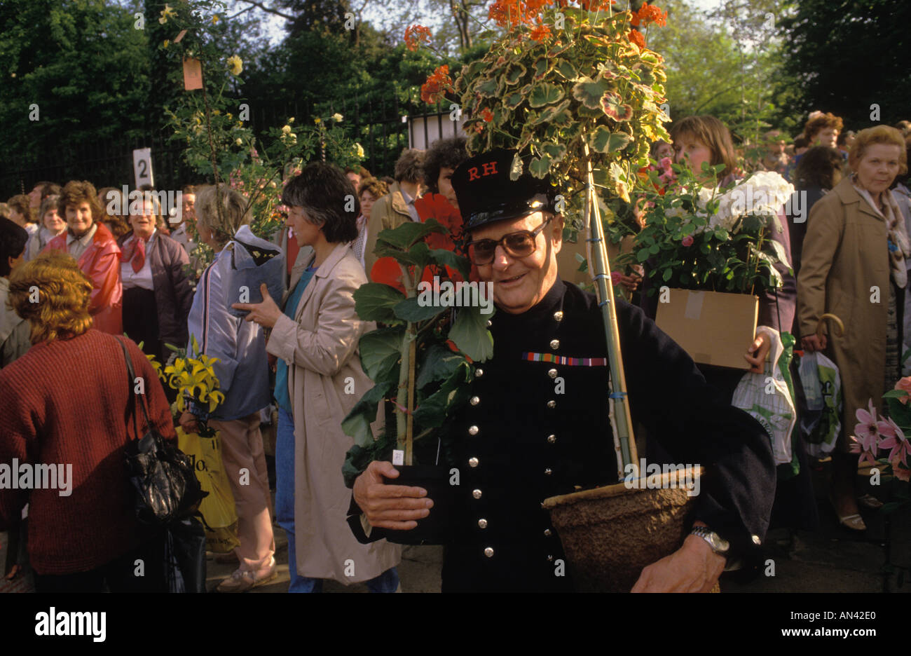 Last day of the Chelsea Flower show 1980s London UK. Chelsea Pensioner in uniform taking home some of the displayed flowers 1984.  HOMER SYKES Stock Photo