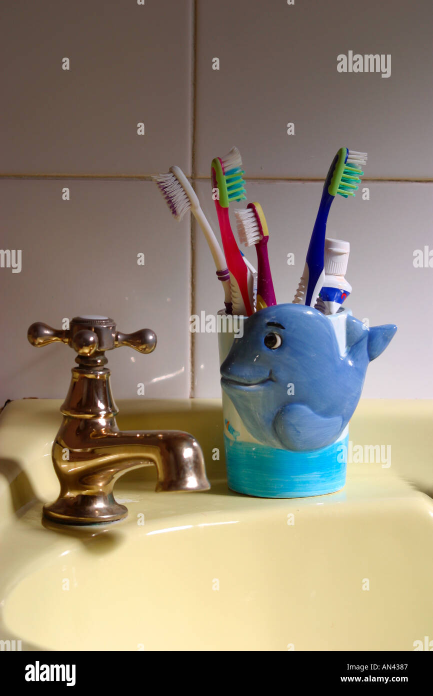 Toothbrushes and mug on sink Stock Photo