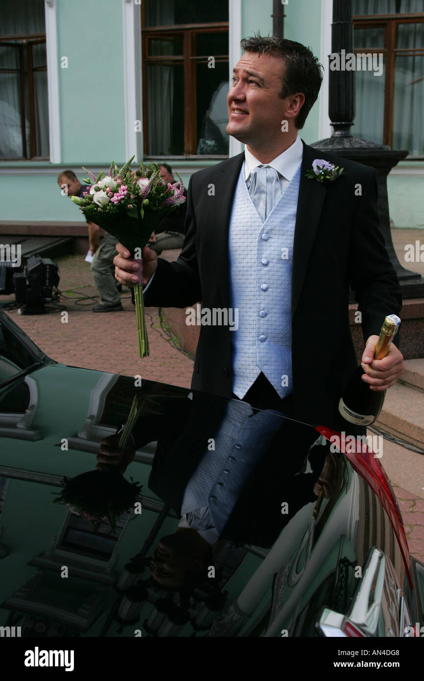 A portrait of a bridegroom in a traditional morning suit pictured on his wedding day holding a bottle of champagne Stock Photo