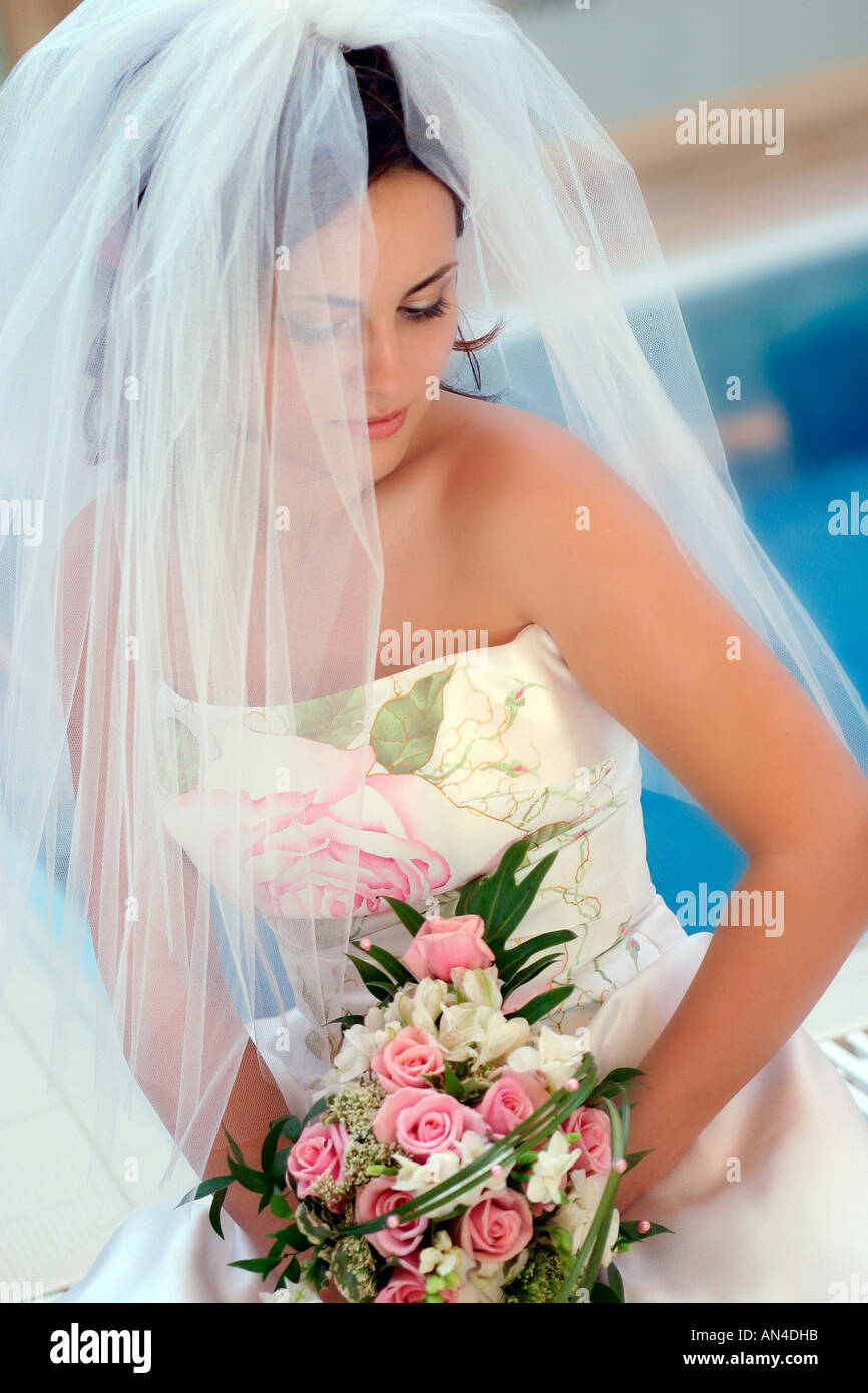 A portrait of a bride on her wedding day pictured holding a bouquet of flowers and wearing a white wedding dress Stock Photo