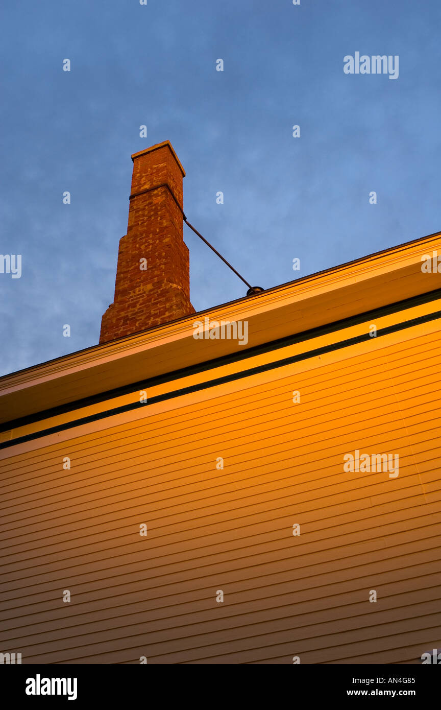 Siding on a clapboard siding house with brick chimney in sunset glow