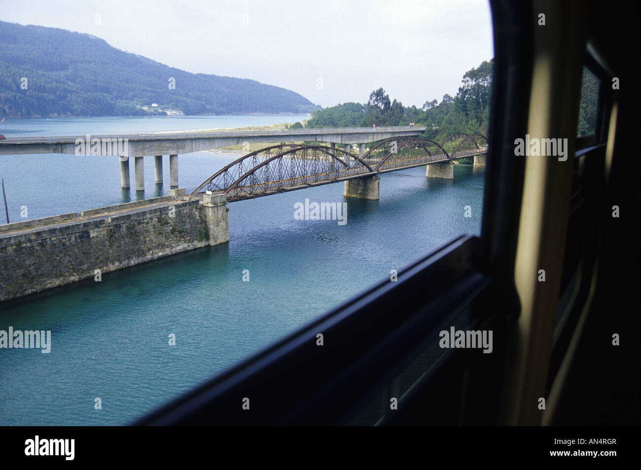 Passing a bridge over Barqueiro ria in Galicia TRANSCANTABRIAN TRAIN through the north of SPAIN Stock Photo
