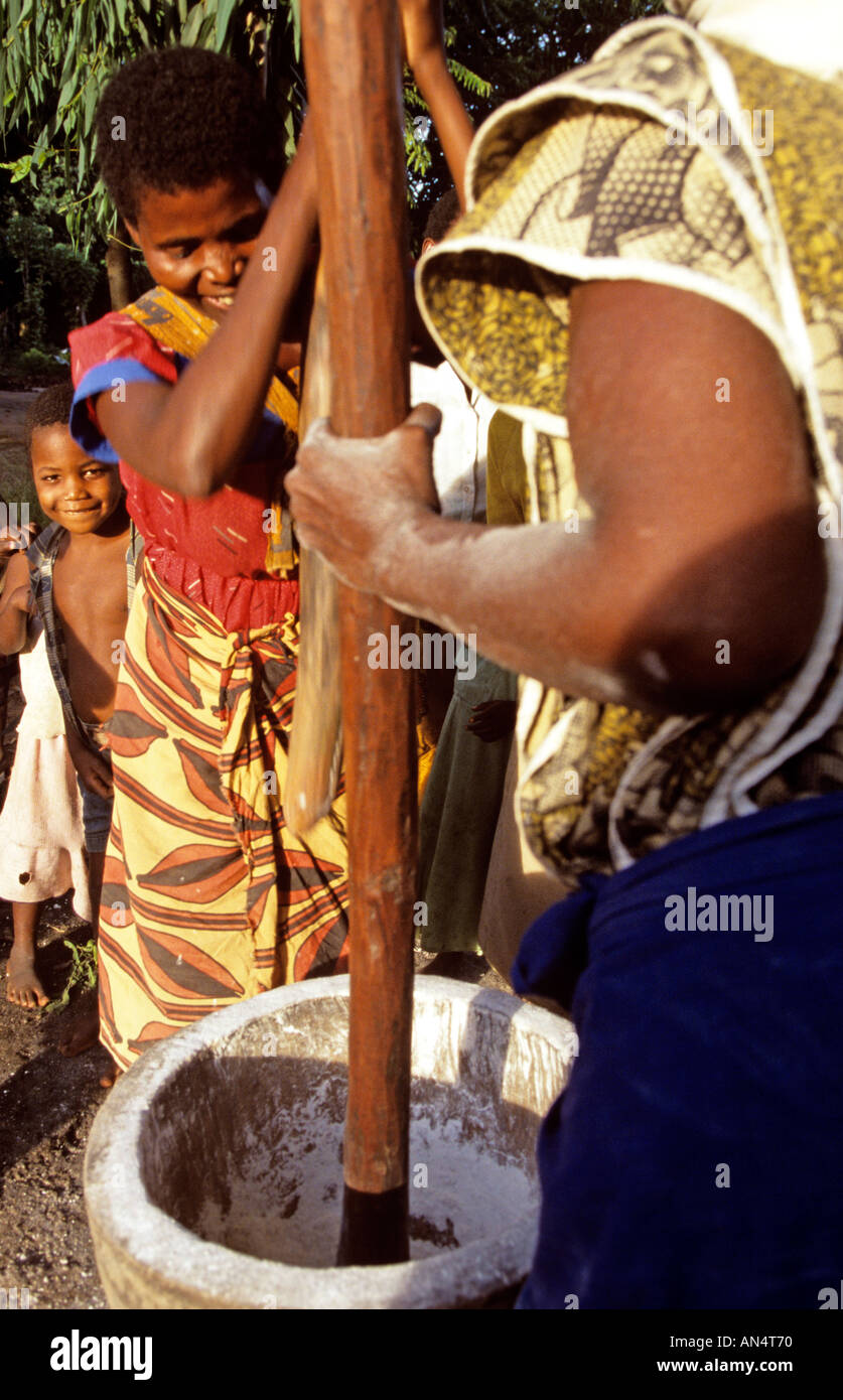 African women pounding rice in a big mortar Stock Photo