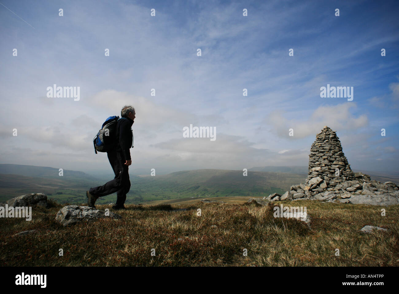 A walker approaches a cairn on Great Coum Cumbria England Stock Photo