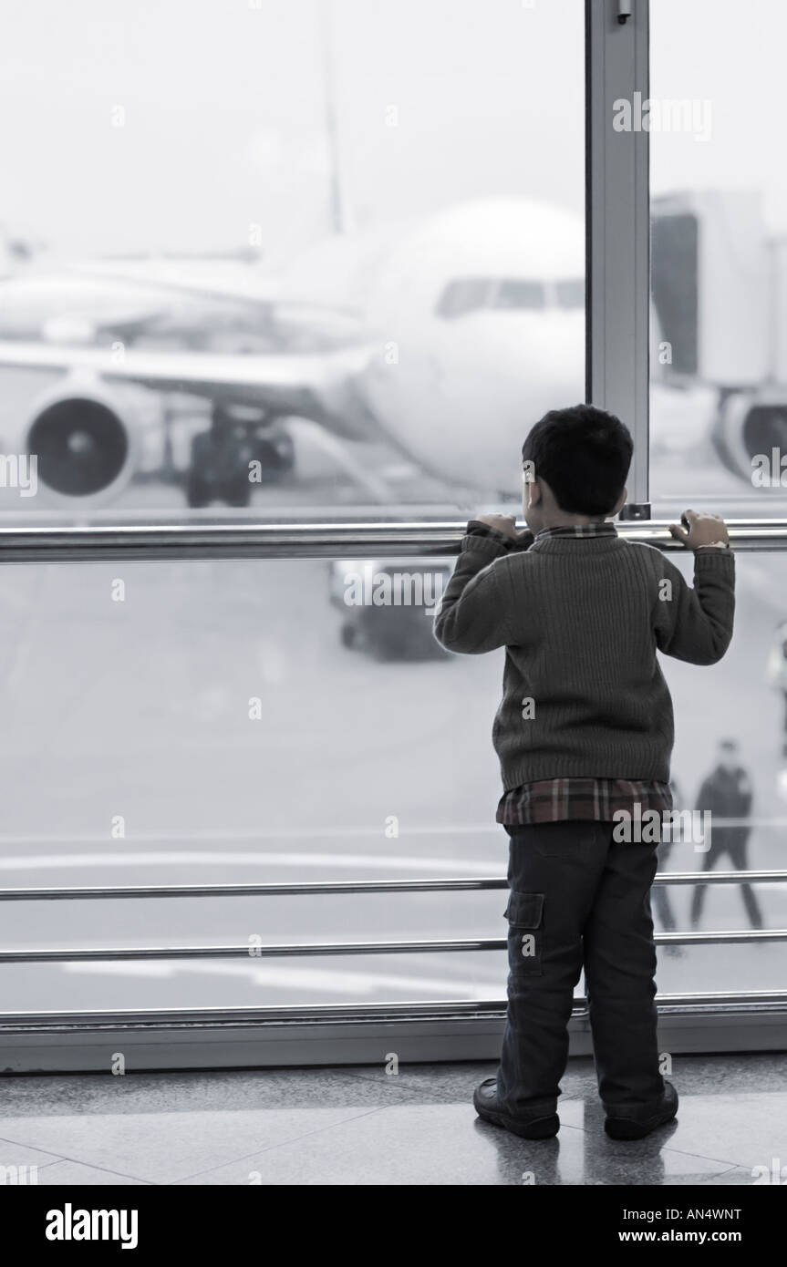 Child alone at the airport looking at a plane through a window Stock Photo Alamy