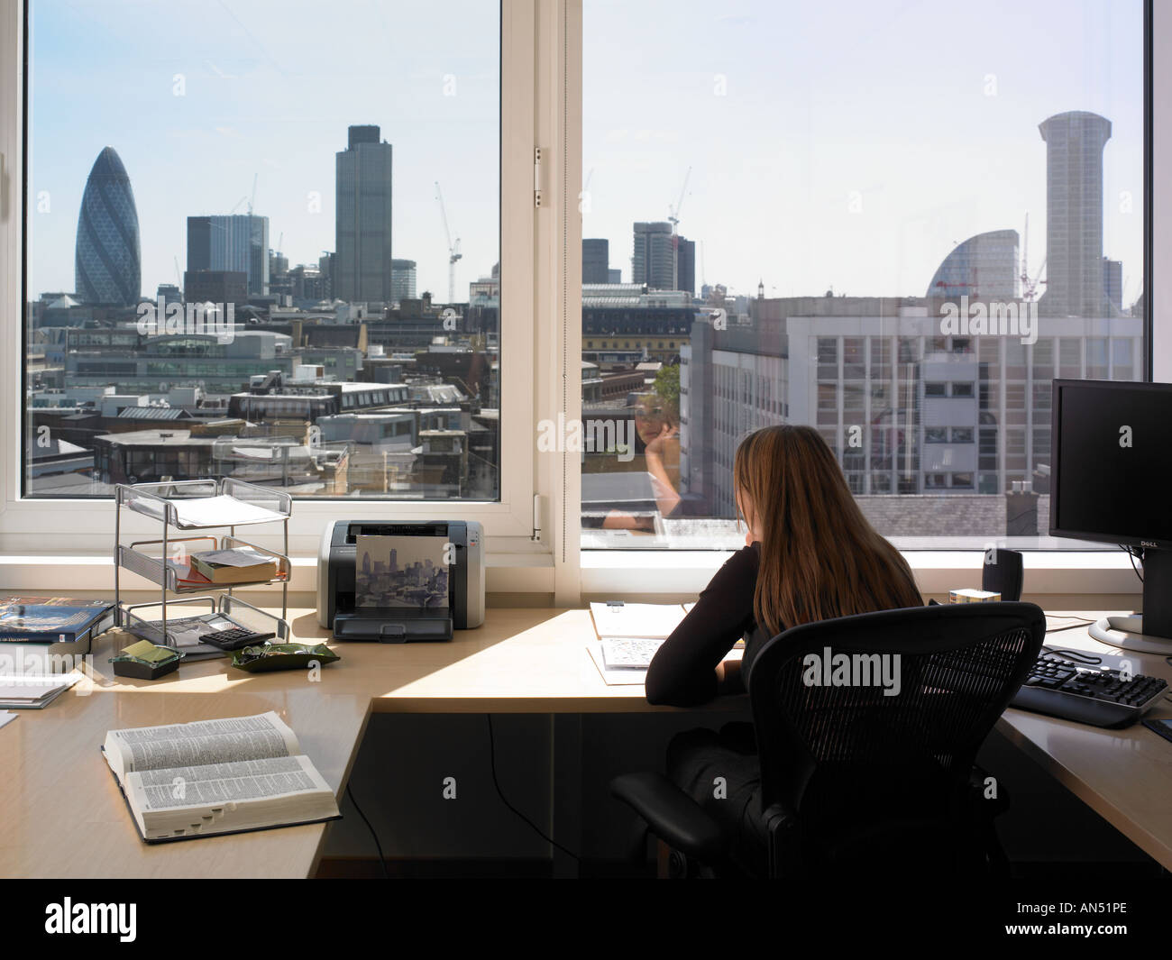 Office life and interiors part two. Female employee sitting with back turned looking through book. Stock Photo