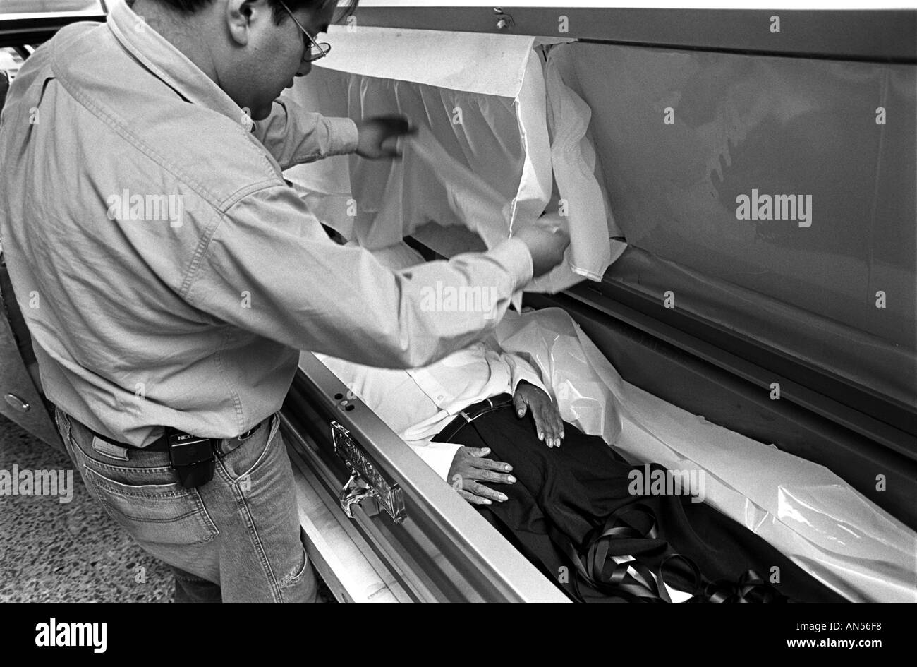 Olimpia funeral home employee Roberto Garcia inspects the body of a