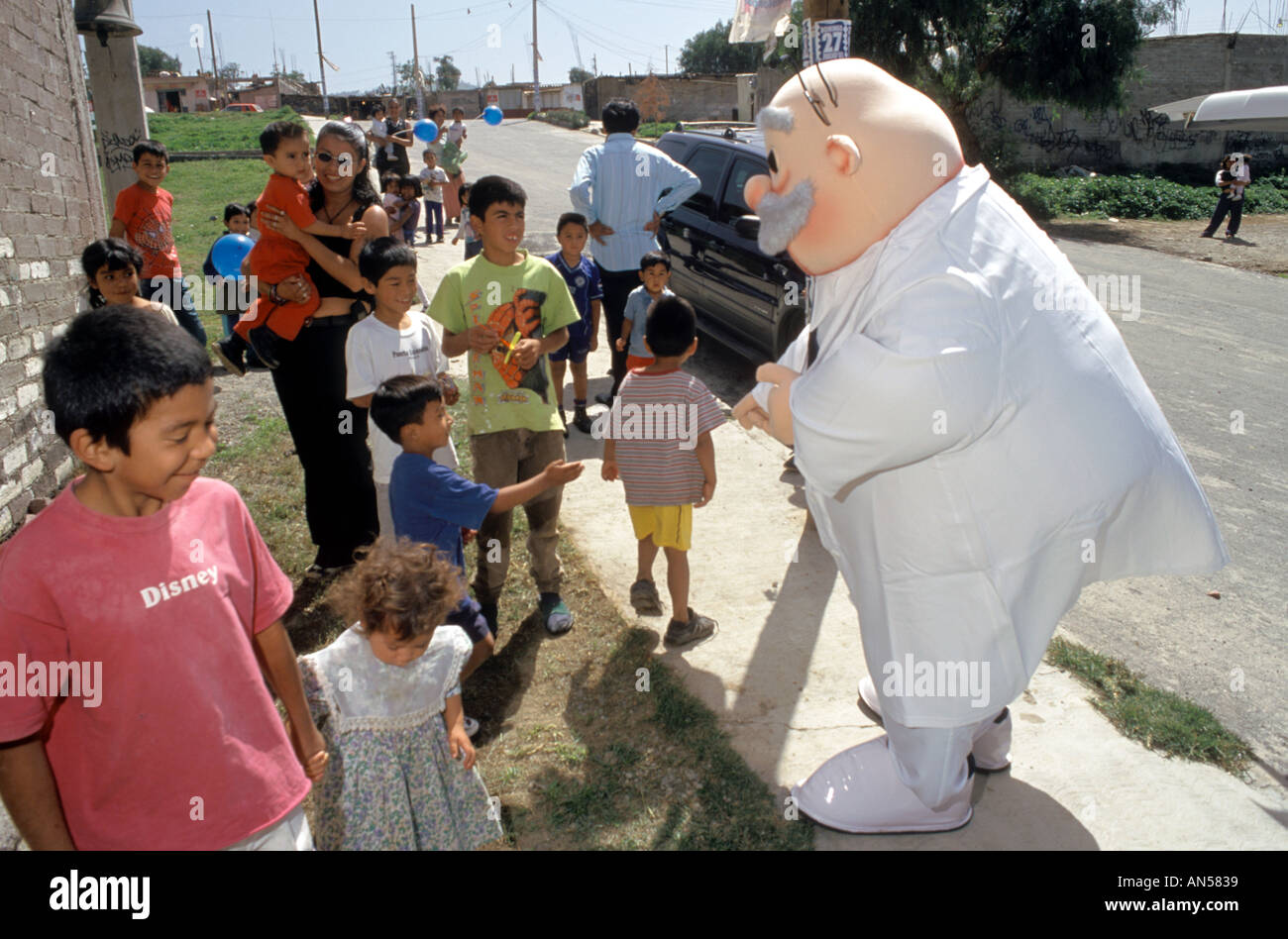 A promotional character for Farmacias Similares attracts children for a community based health care program outside Mexico City  Stock Photo
