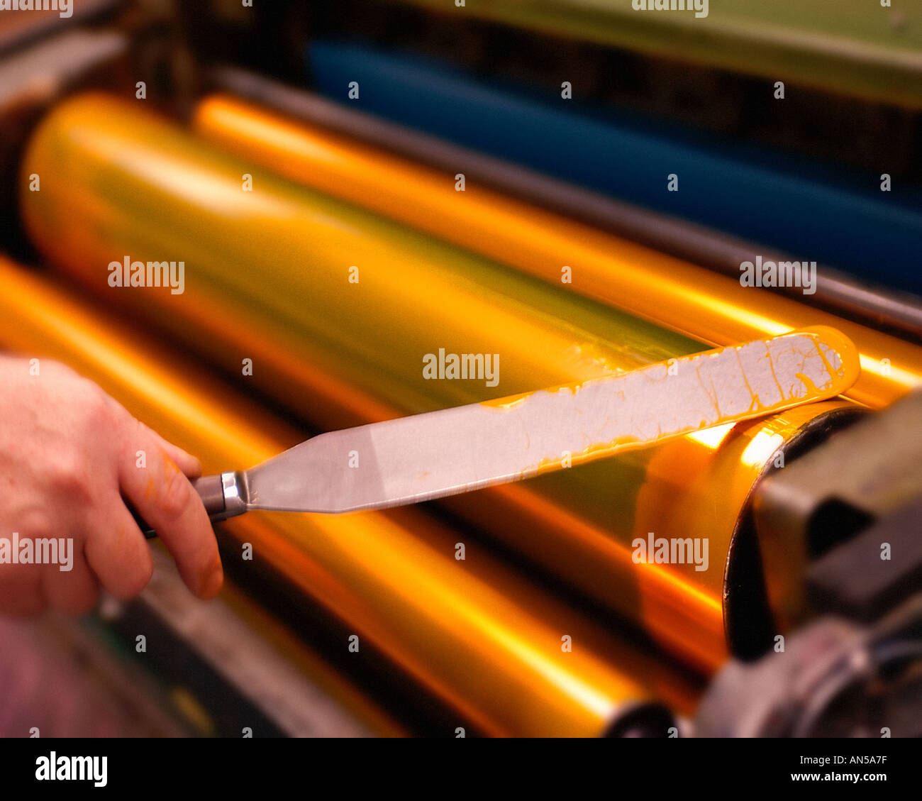 PRINTER APPLYING INK TO ROLLERS OF PRINTING PRESS Stock Photo