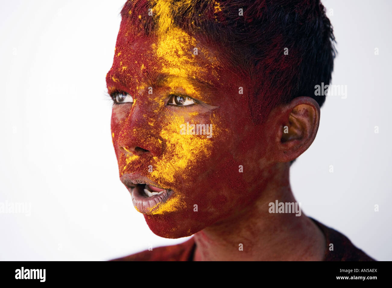 Indian boy covered in maroon and ochre coloured powder Stock Photo