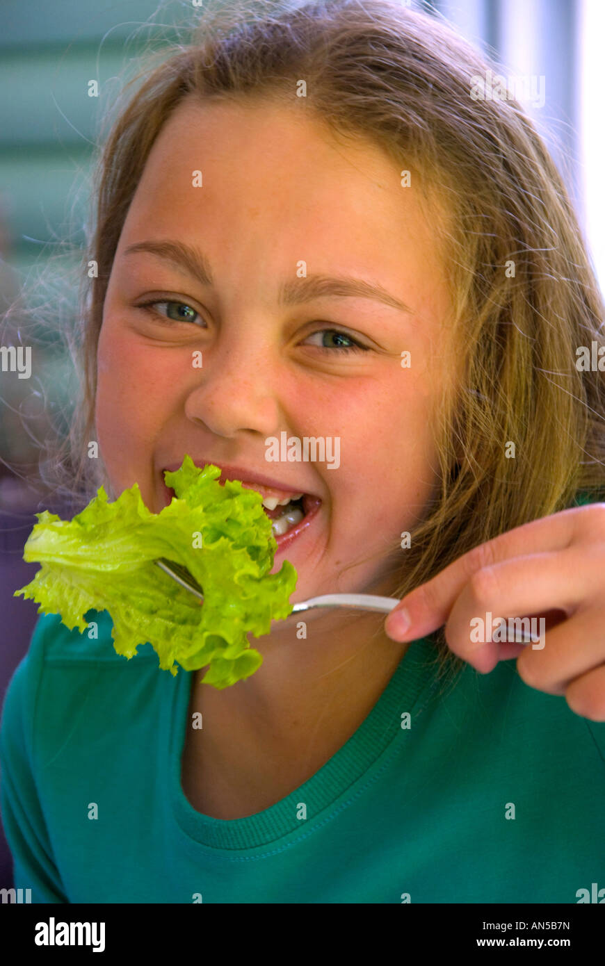Pretty young girl eating lettuce from a fork Stock Photo