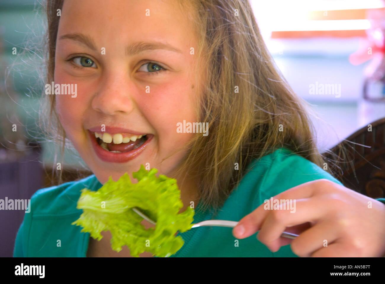 Pretty young girl eating lettuce from a fork Stock Photo
