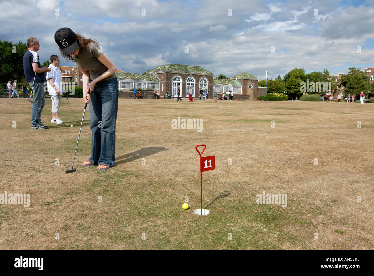 Woman playing mini golf putting at Worthing Marine ^gardens. Stock Photo