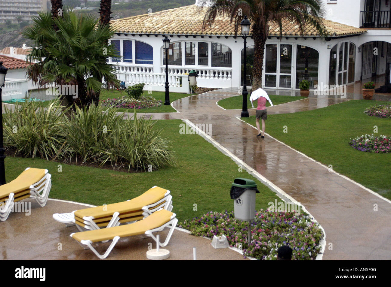 Heavy rain falling on a holiday hotel with a lone figure running in the rain Stock Photo