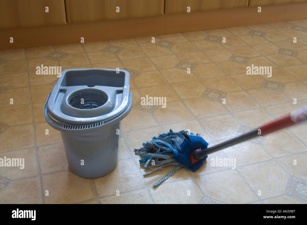 Studio Close up washing a kitchen floor using a blue fabric mop and bucket Stock Photo