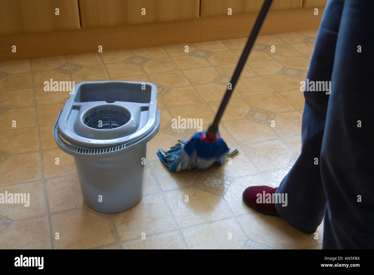 Studio Close up woman washing a kitchen floor with a blue fabric mop Stock Photo