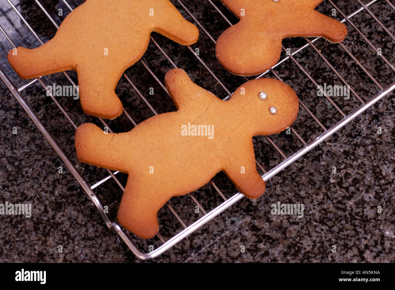 Gingerbread men cooling on wire rack on granite work surface Stock