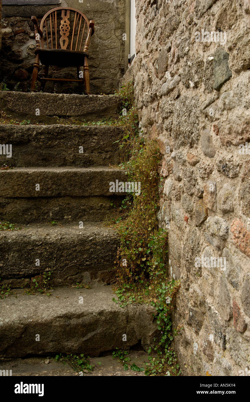 Traditional stone steps at the side of a building on Dartmooor with an old wooden chair at the top Stock Photo