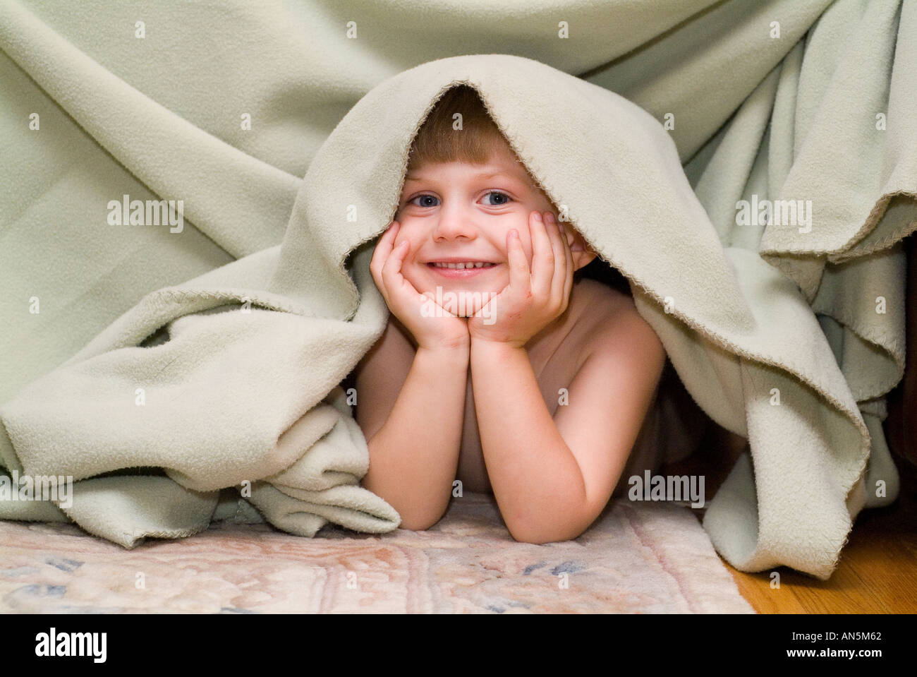 Smiling boy playing under blanket playful children Stock Photo Alamy