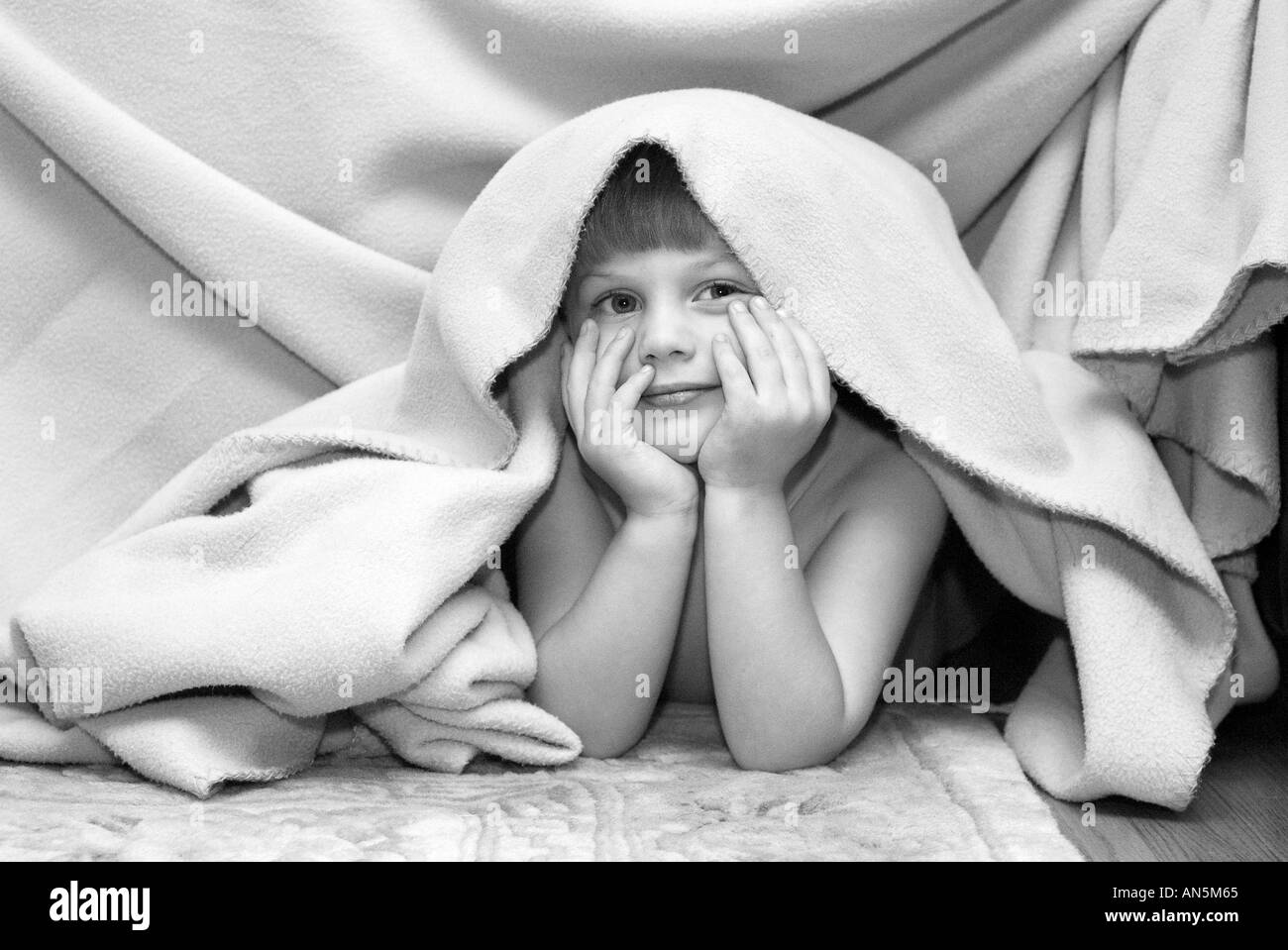 Small boy smiling hiding under blanket Stock Photo