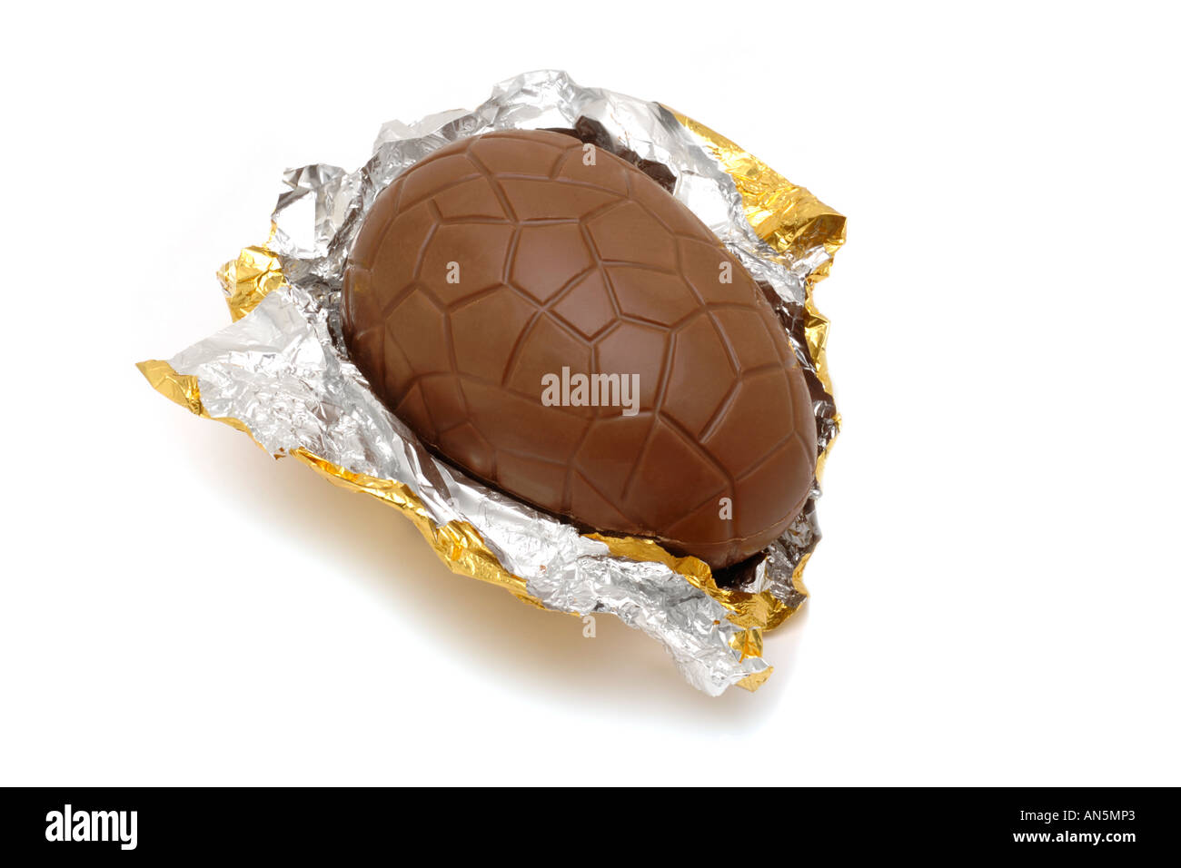 Milk chocolate easter egg in gold foil on white background Stock Photo