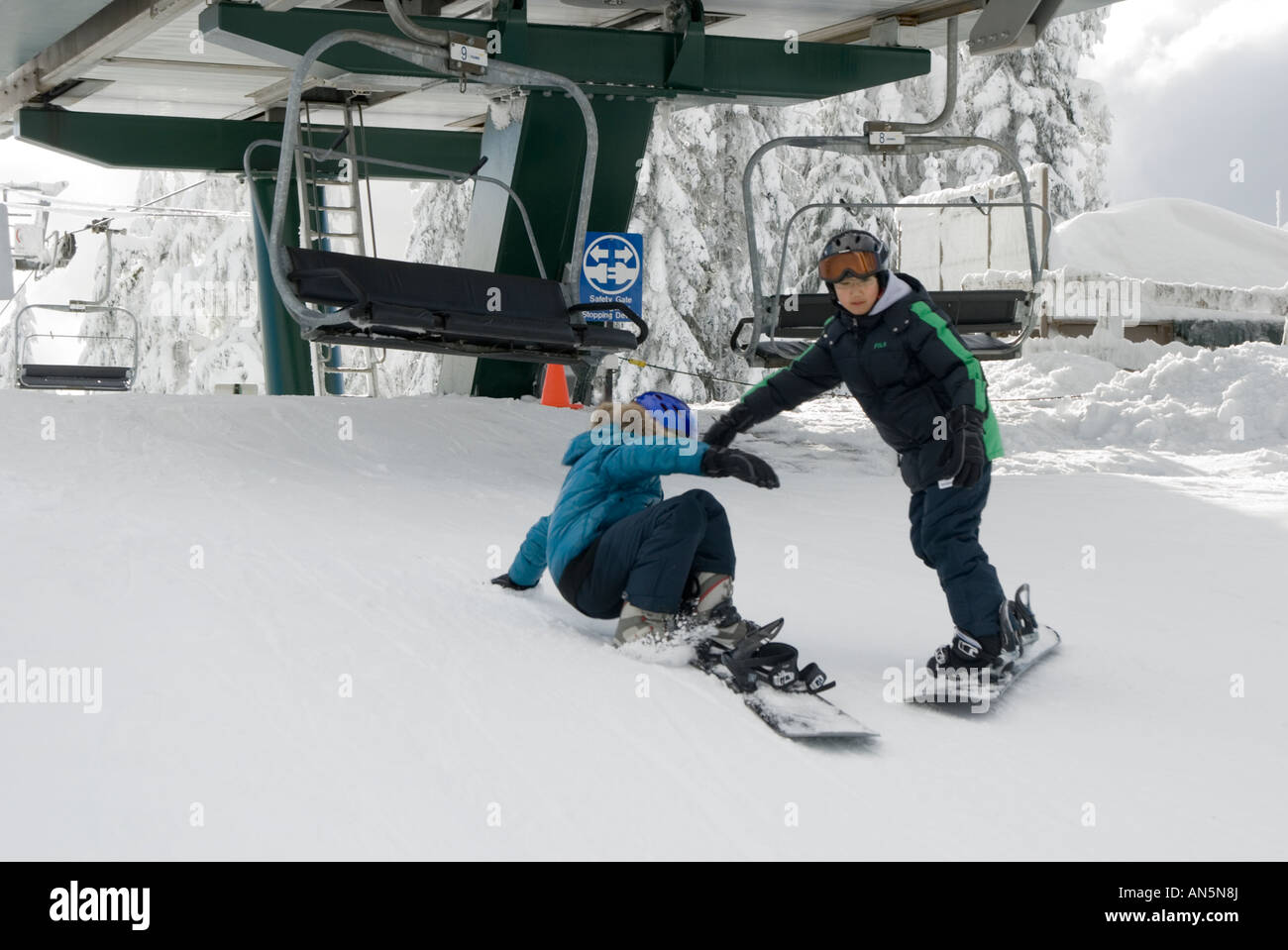Kids on snowboards getting off chairlift Stock Photo Alamy