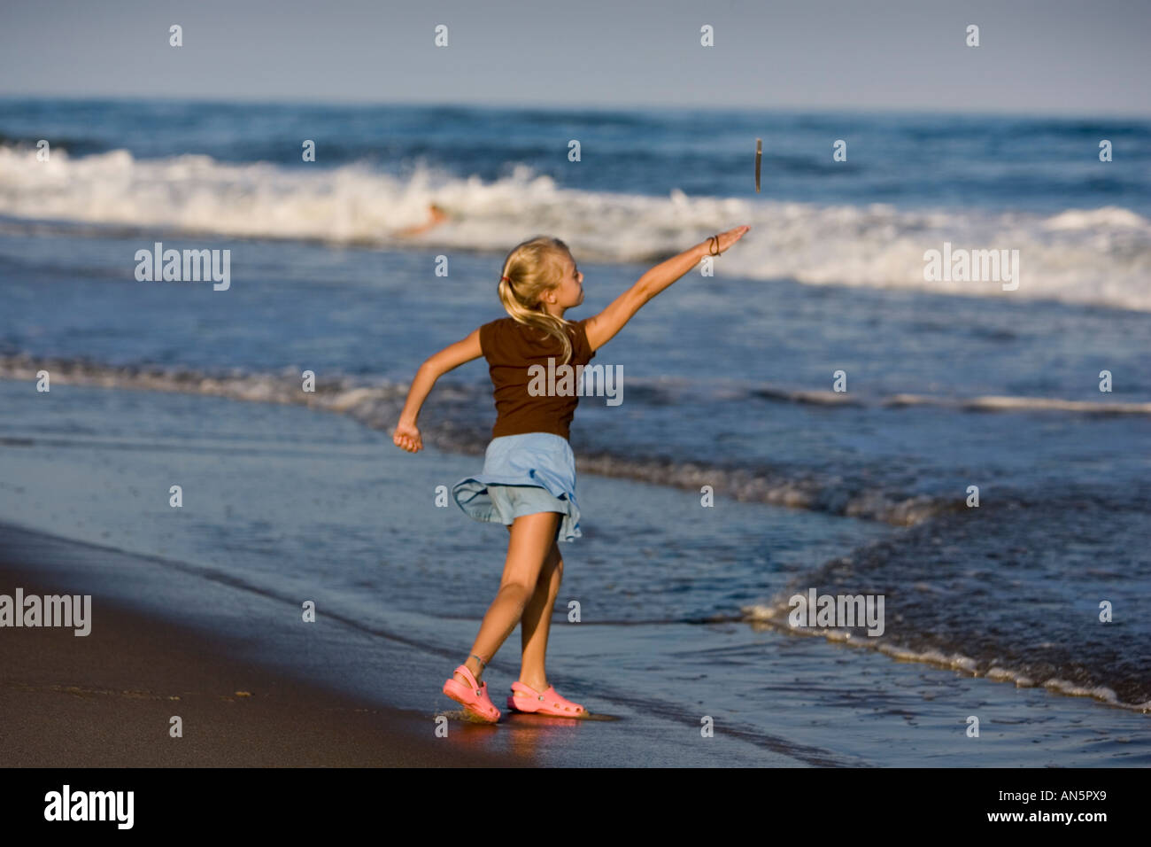 Young girl throwing a stick into the ocean Stock Photo Alamy