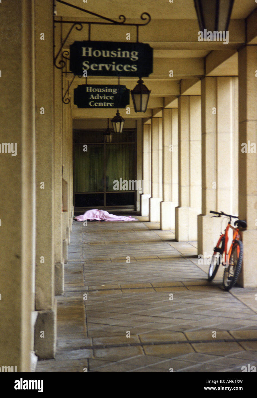 Homeless man sleeping rough in the cover of the housing services offices in Brighton England