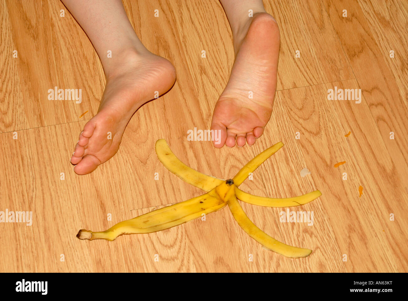 A young woman slips on a banana peal. She has fallen and she can't get