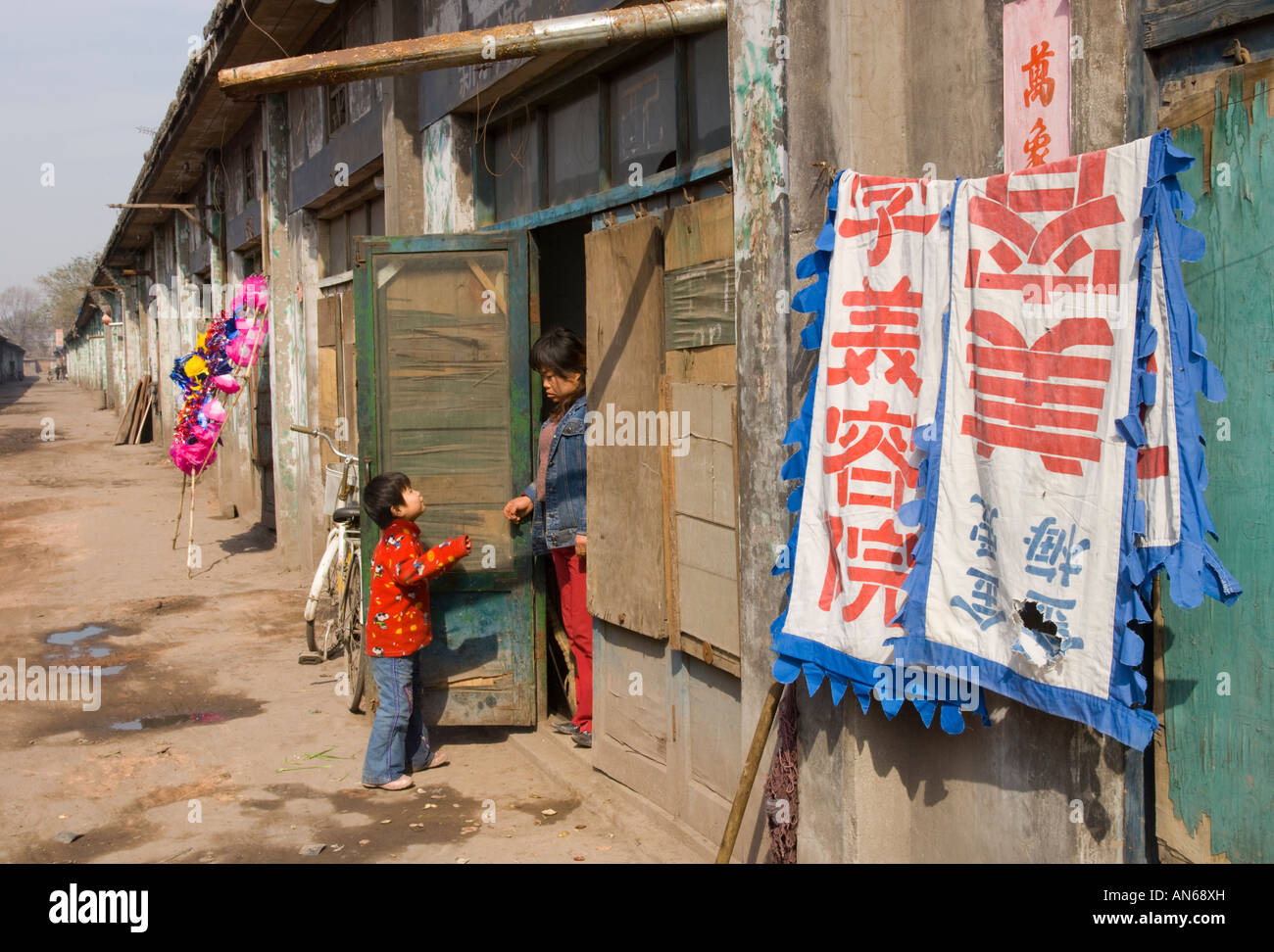 China Shanxi Pingyao poor neighbourhood child and mother standing at entrance to their house Stock Photo