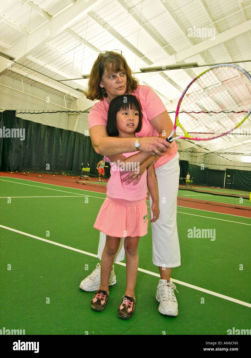 instructor helps girl learn how to hold racket correctly during tennis
