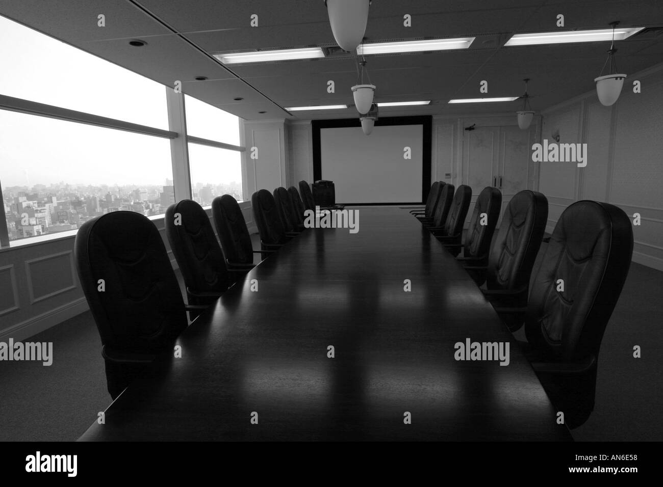 Long wooden boardroom table surrounded by expensive leather chairs in a large company boardroom Stock Photo