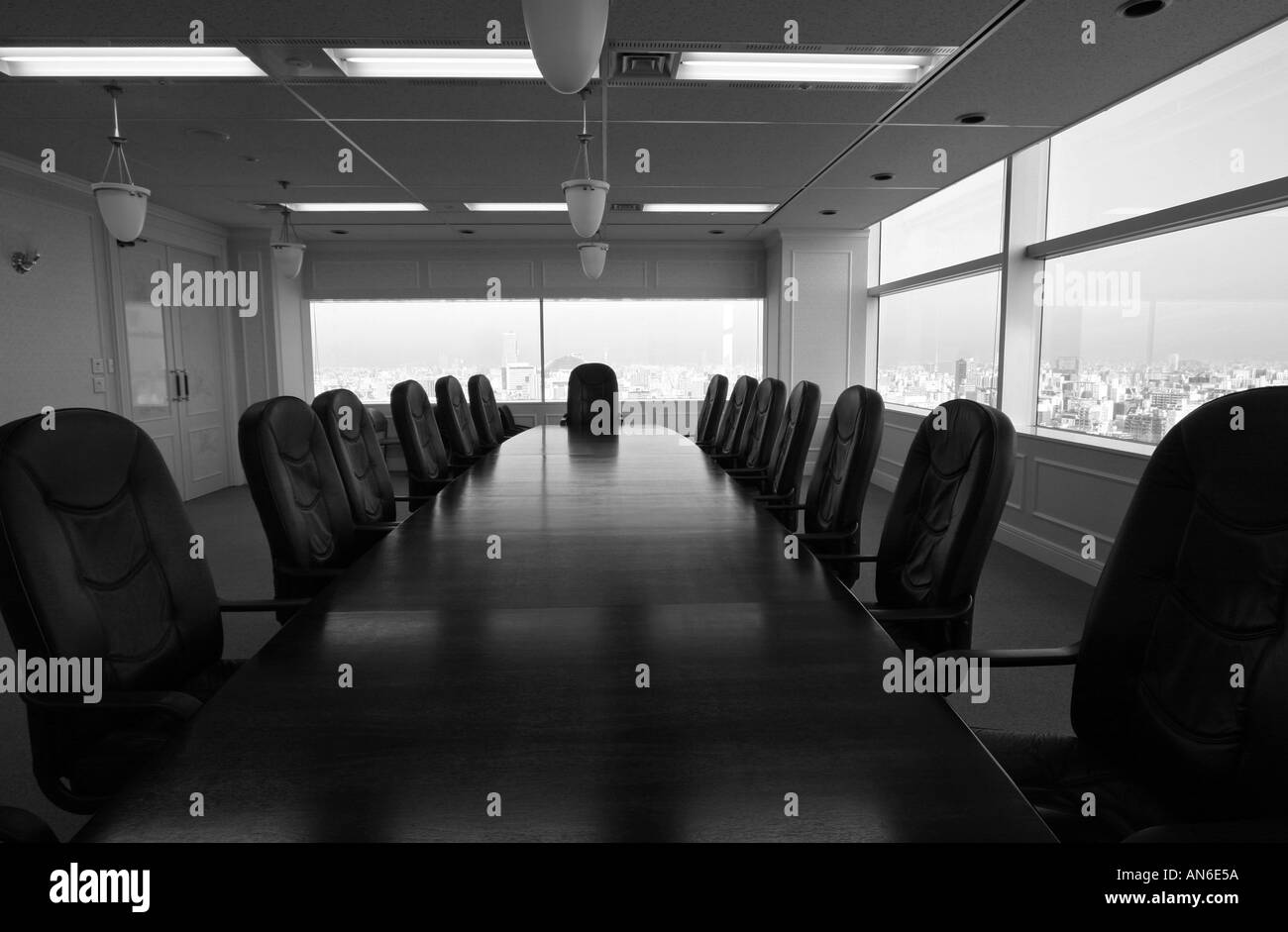 Long wooden boardroom table surrounded by expensive leather chairs in a large company with city vista view Japan Asia Stock Photo