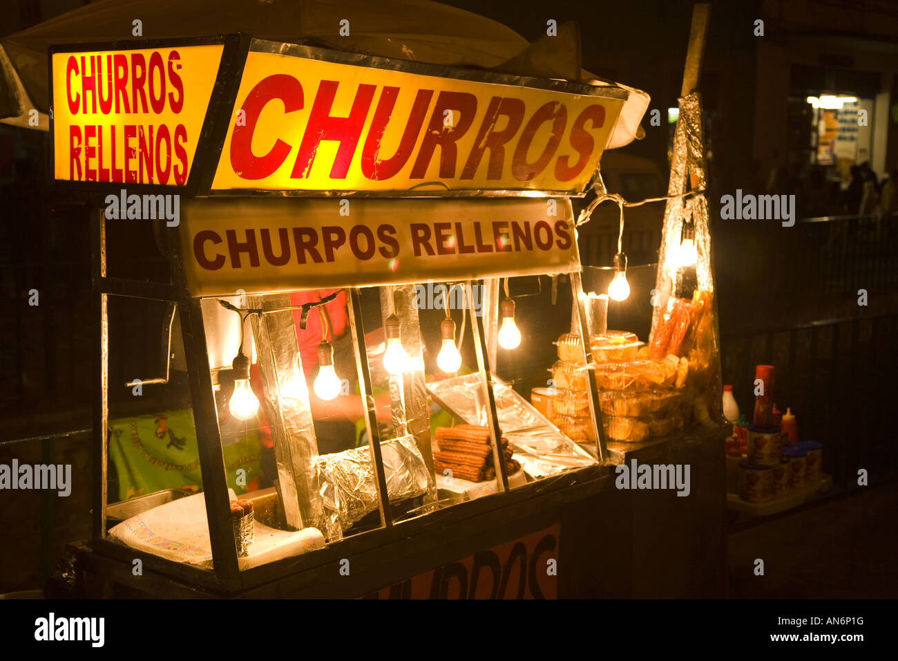MEXICO Guanajuato Street vendor selling churros rellenos at night light bulbs at food booth Stock Photo