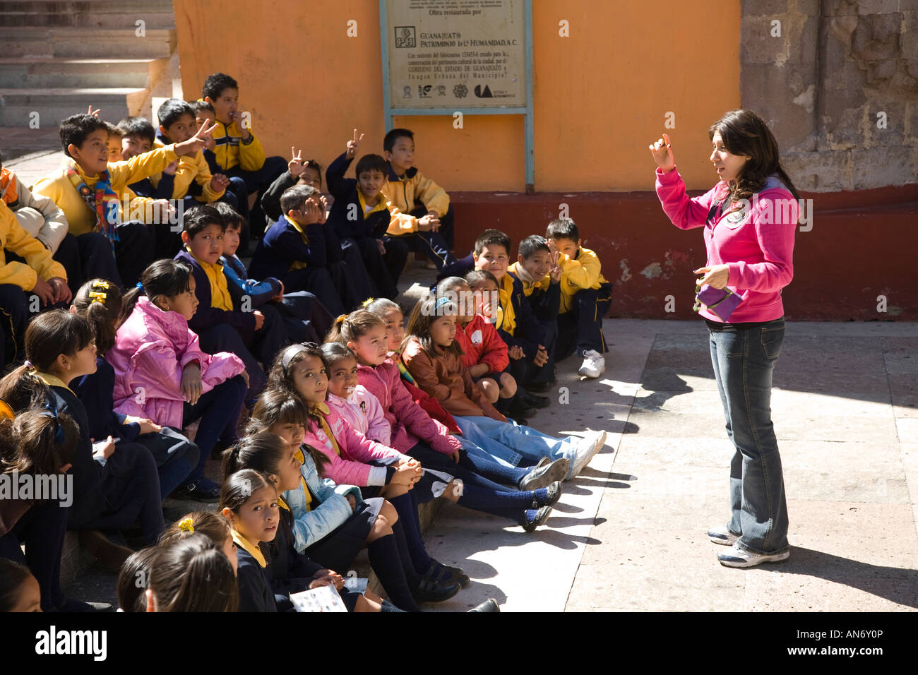 MEXICO Guanajuato Teacher instruct children sitting outside Templo de San Diego field trip from school Stock Photo