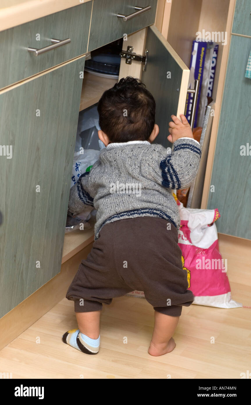 Naughty baby boy going through cupboard Stock Photo