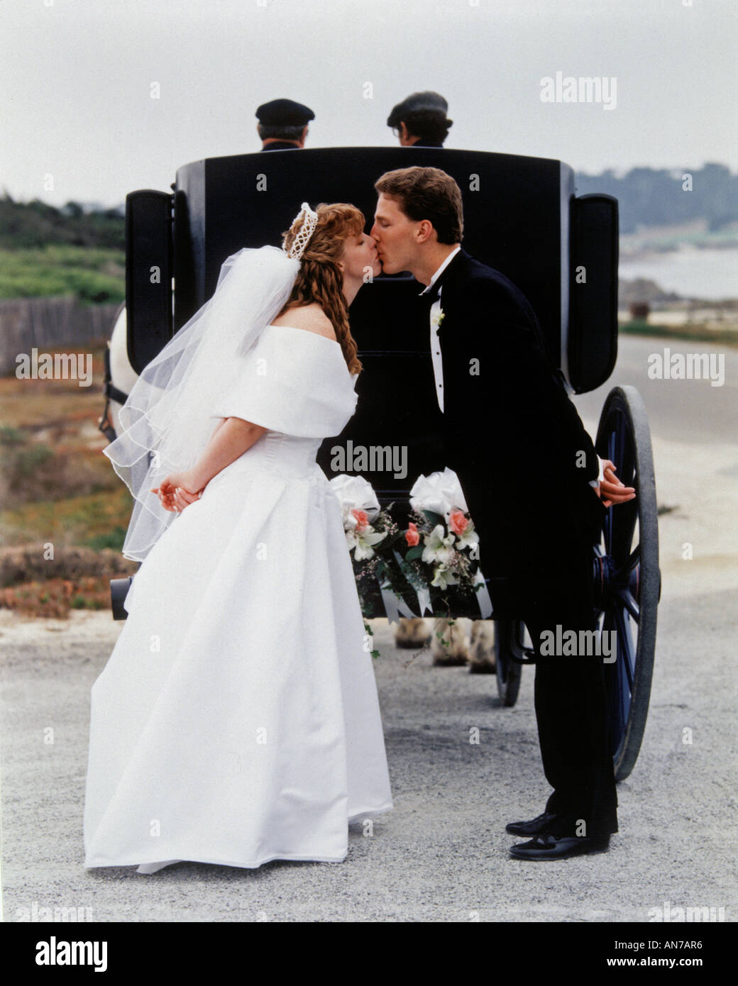Bride groom kiss behind a horse drawn carriage MODEL RELEASED Stock Photo