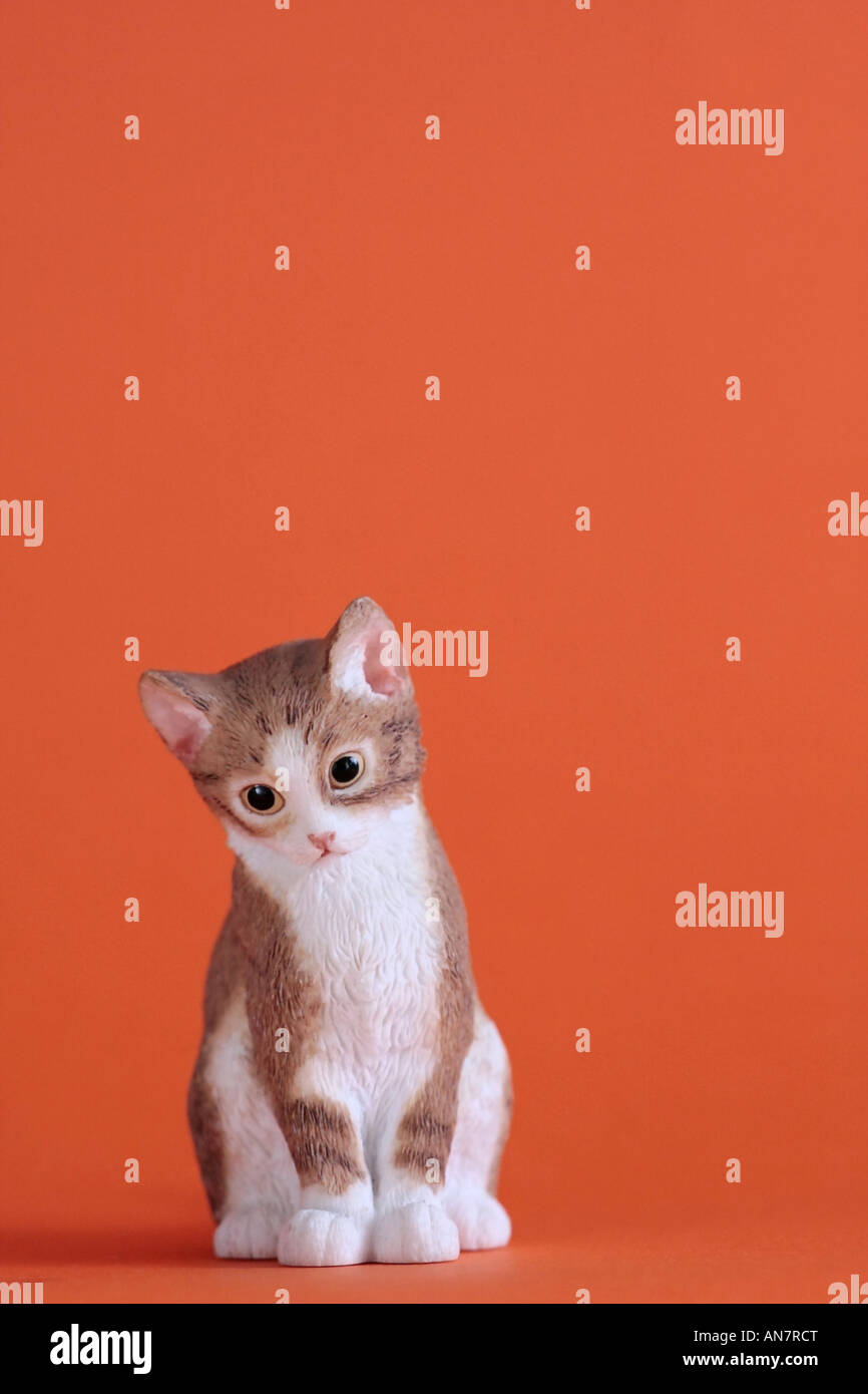 Ceramic model of cute kitten against plain coloured background Stock Photo