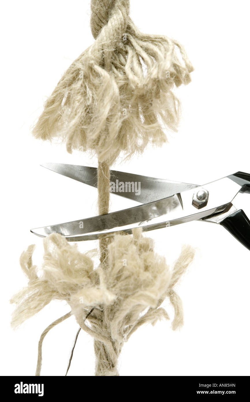 Cutting A Rope With Scissors Against White Background Stock Photo